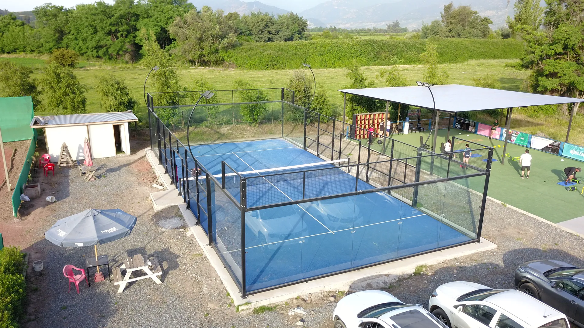 La cancha de pádel de superficie azul y paredes de vidrio del club